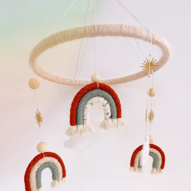Decorative mobile with rainbow shapes and tassels on a light background