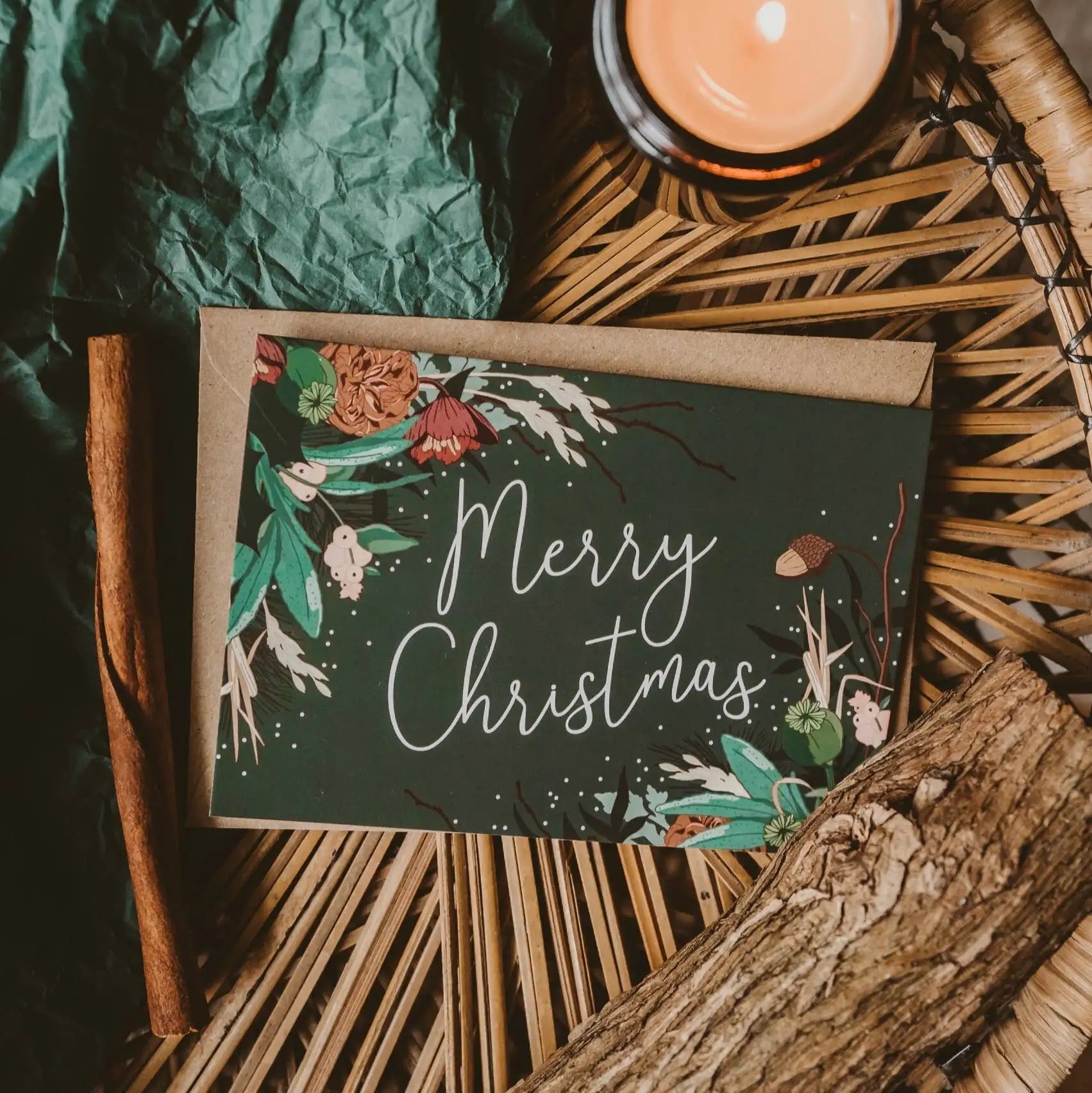 Christmas card with floral design and 'Merry Christmas' text on a rustic background with candles and leaves.