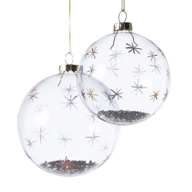 Two clear glass Christmas ornaments with star designs on a white background
