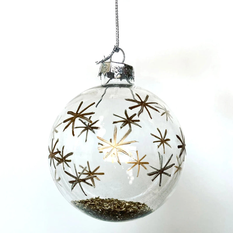 Clear glass Christmas ornament with gold star designs on a white background