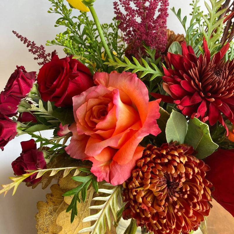 Colorful bouquet of flowers including roses and asters on a white background
