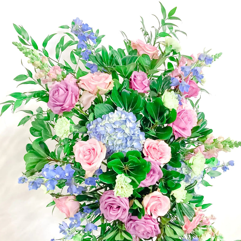 Bouquet of pink roses, blue hydrangeas, and green leaves on a white background