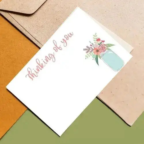 Greeting card with 'Thinking of you' text and floral design on a textured surface.