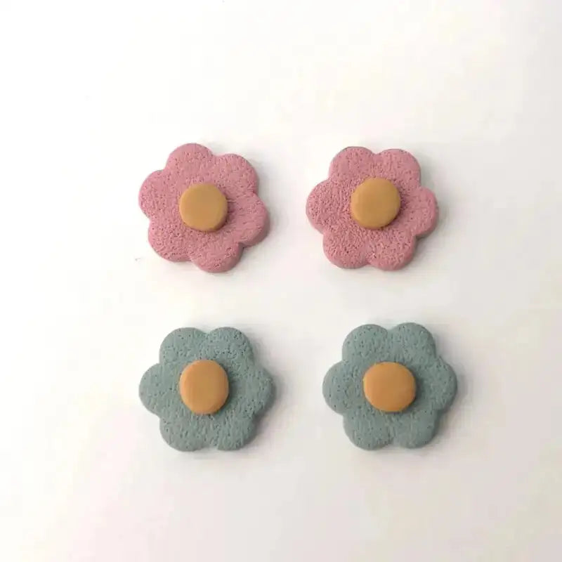 Two pairs of flower-shaped earrings in pink and blue with a brown center on a white background.