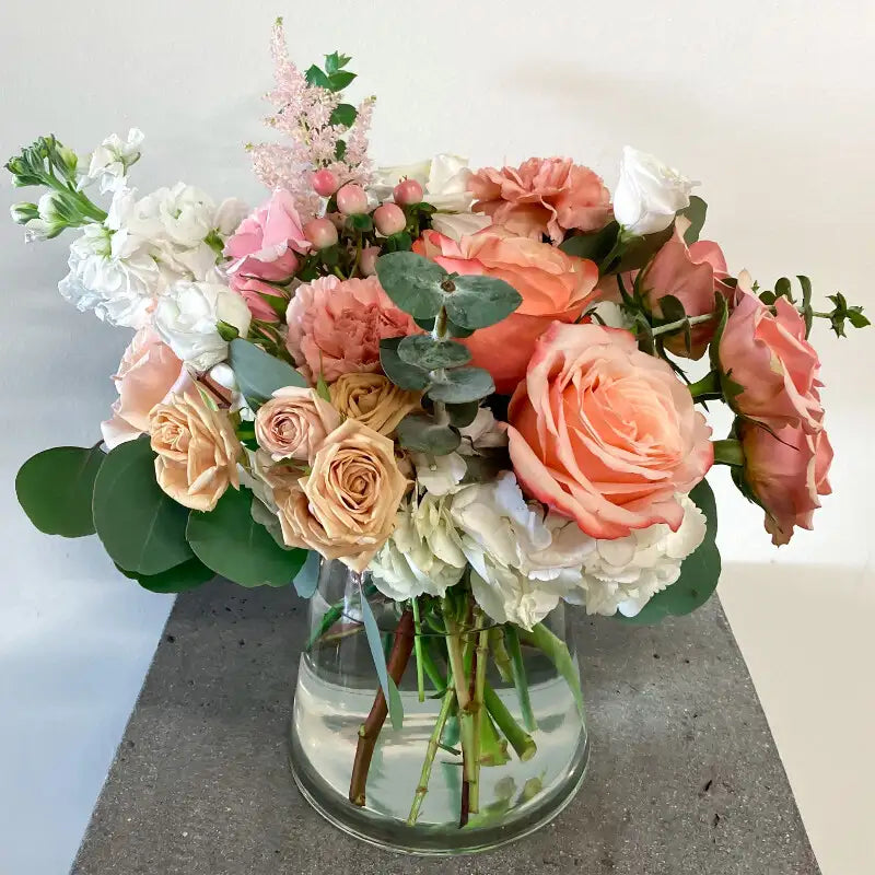 Bouquet of pink and white flowers in a clear vase on a light background