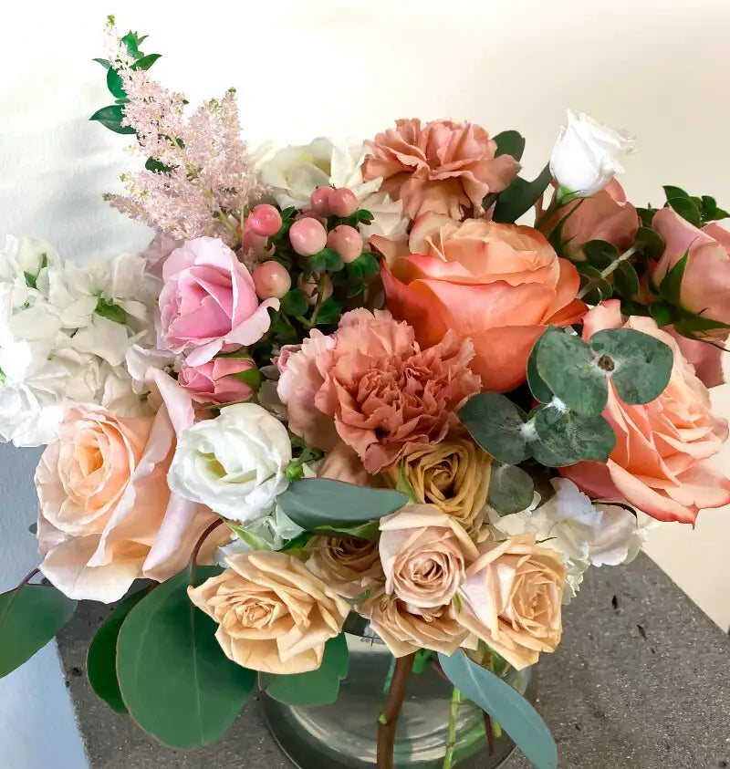 Bouquet of flowers with pink, orange, and white roses on a light background