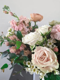 Bouquet of pink and white flowers with green leaves on a light gray background
