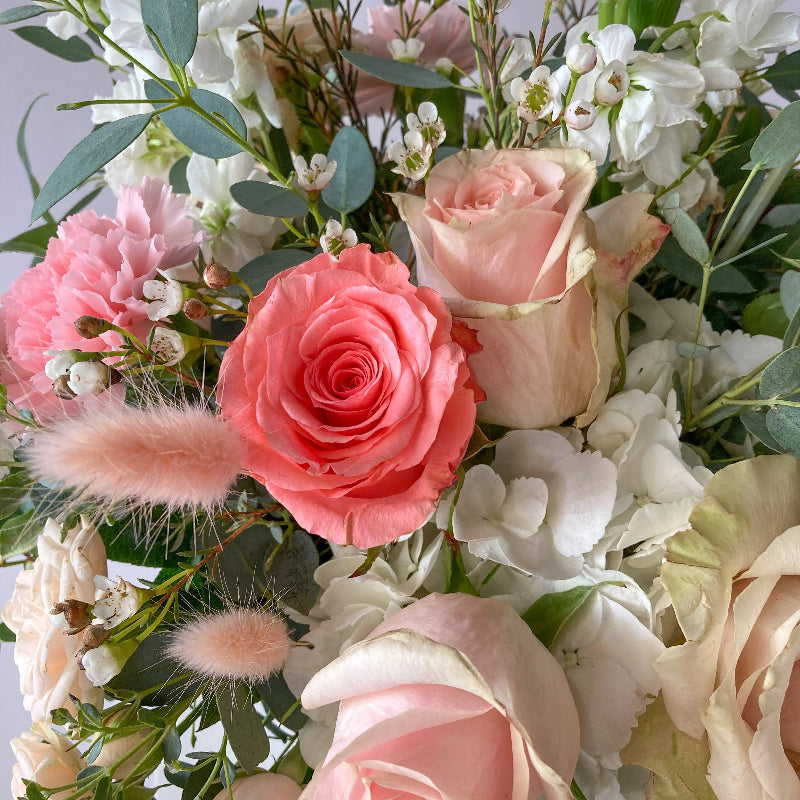 Bouquet of pink and white flowers with greenery on a light background