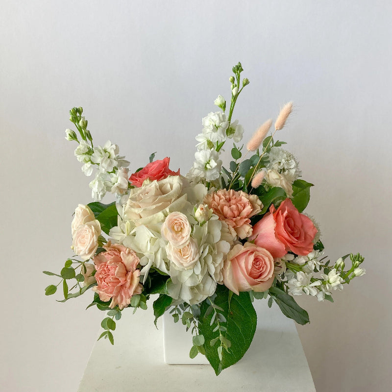 Bouquet of pink and white flowers with green leaves on a light background