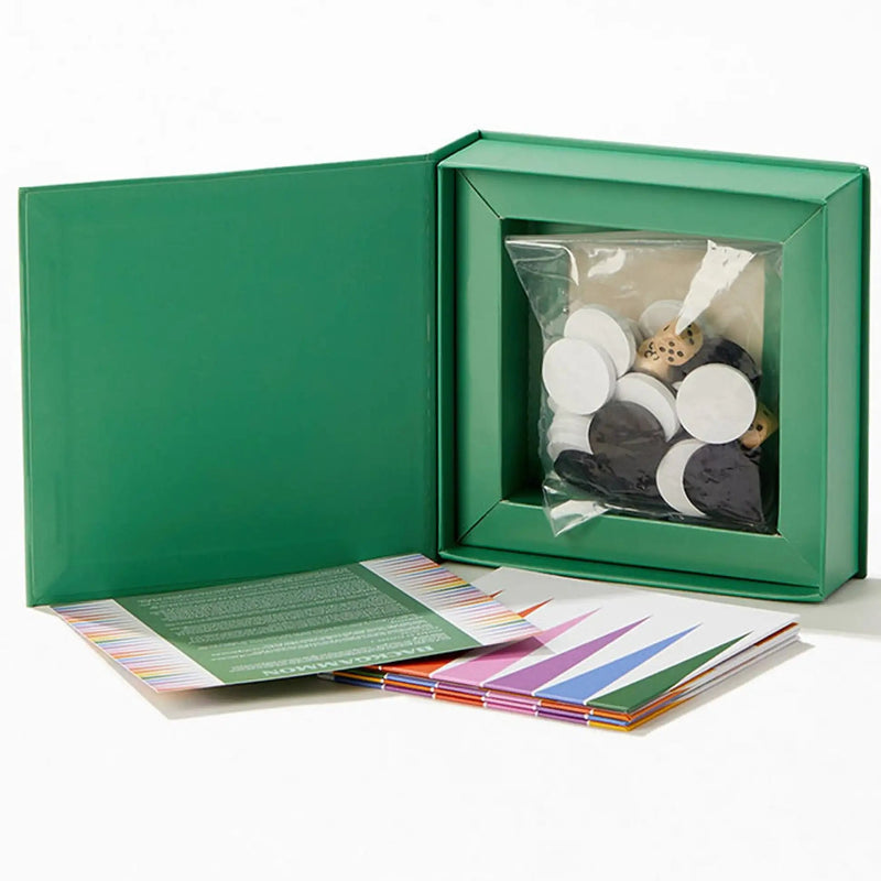 Green box with a clear window containing small round objects, on a white background