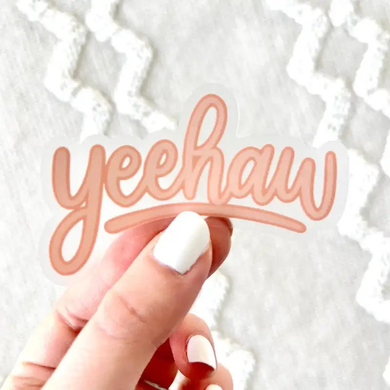 Hand holding a 'yeehaw' sign against a textured white background