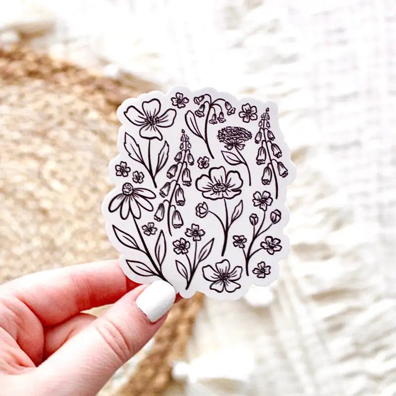 Hand holding a floral sticker with a blurred natural background