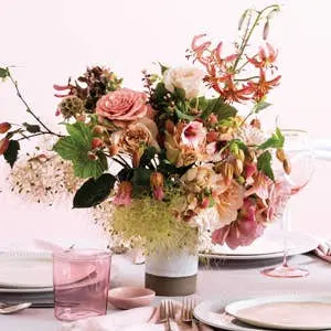 Decorative floral arrangement on a table with plates and glasses.