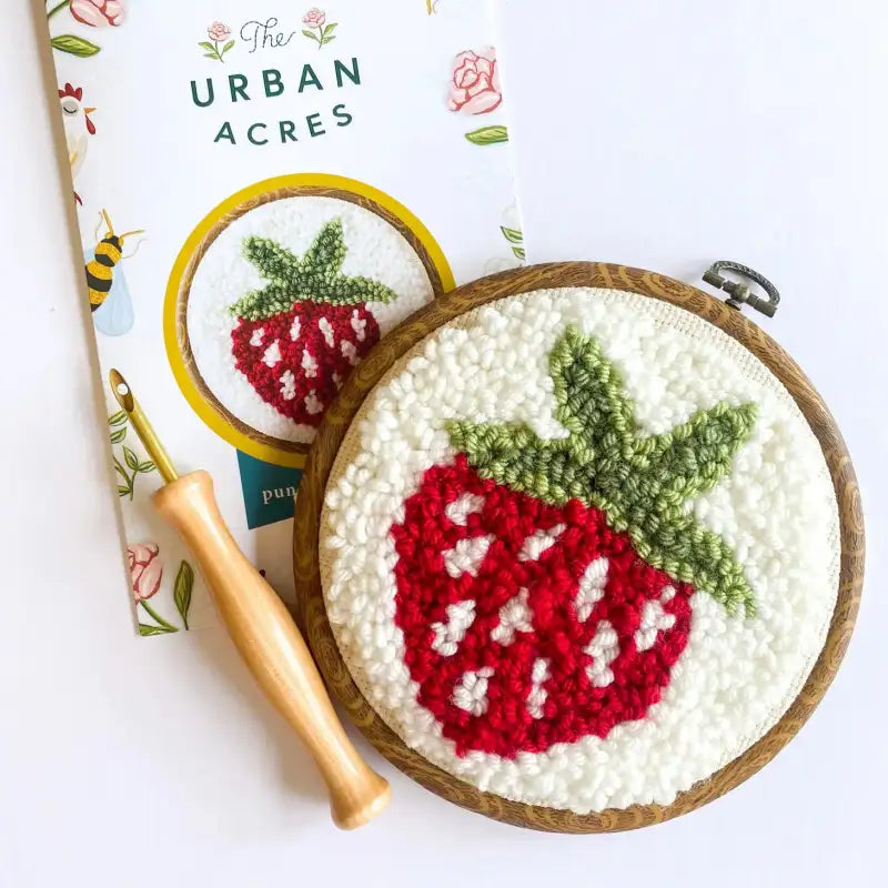 Embroidery hoop with strawberry design on a white background, featuring 'The Urban Acres' brand.
