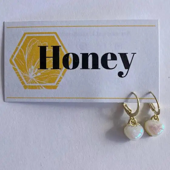 Gold earrings with heart-shaped pearl drops on a 'Honey' branded card.