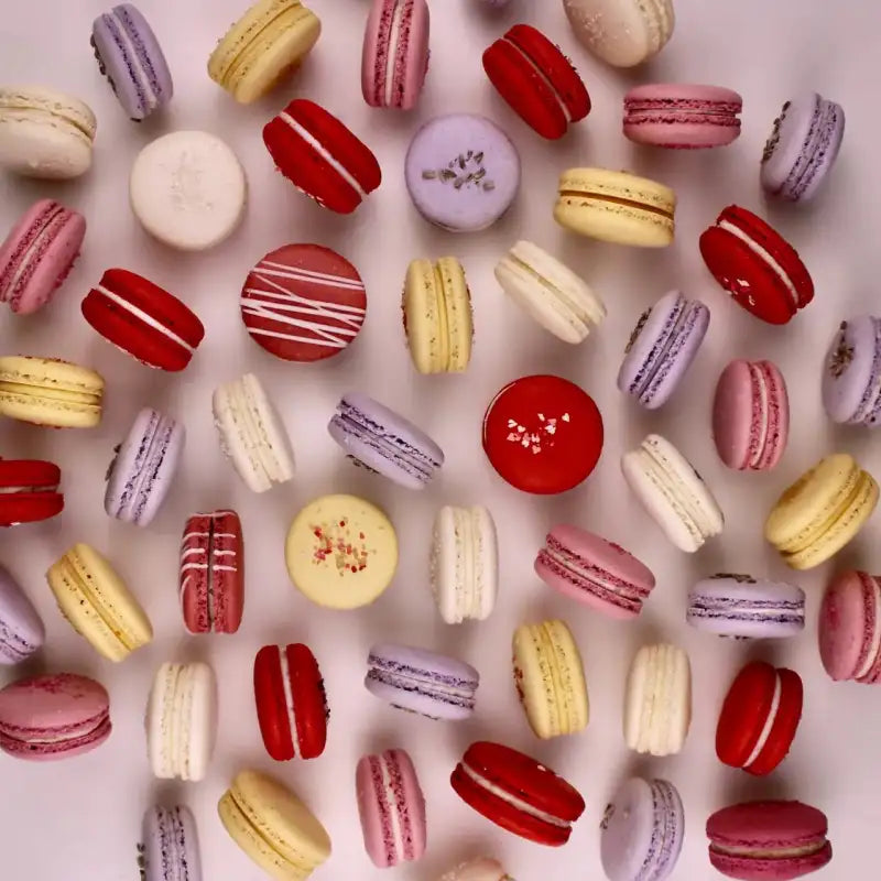 Assorted colorful macarons on a light pink background