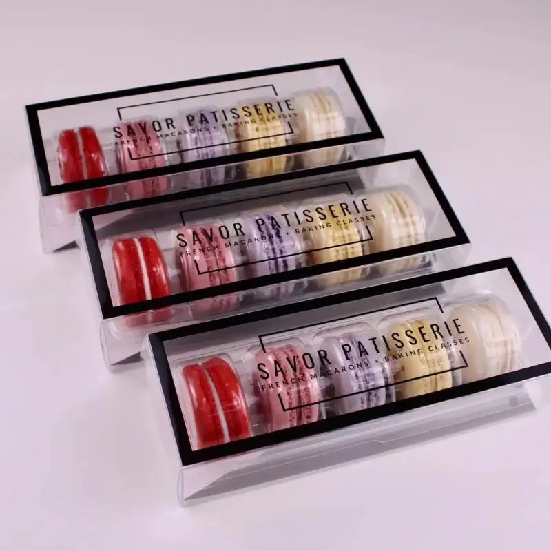 Three packages of Savor Patisserie macarons on a white background