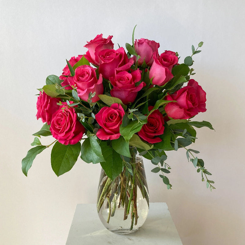 Bouquet of pink roses in a clear vase on a light background