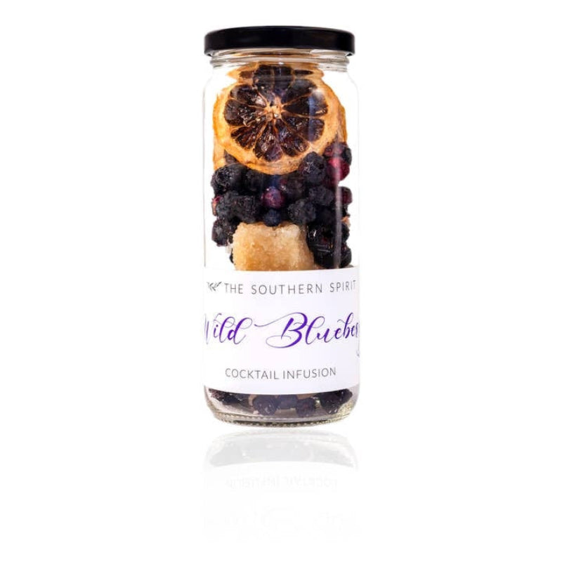 A clear glass jar with a black lid containing a cocktail infusion blend with dried orange slices, blueberries, and a sugar cube. The white label reads 'THE SOUTHERN SPIRIT' and 'Wild Blueberry COCKTAIL INFUSION'.