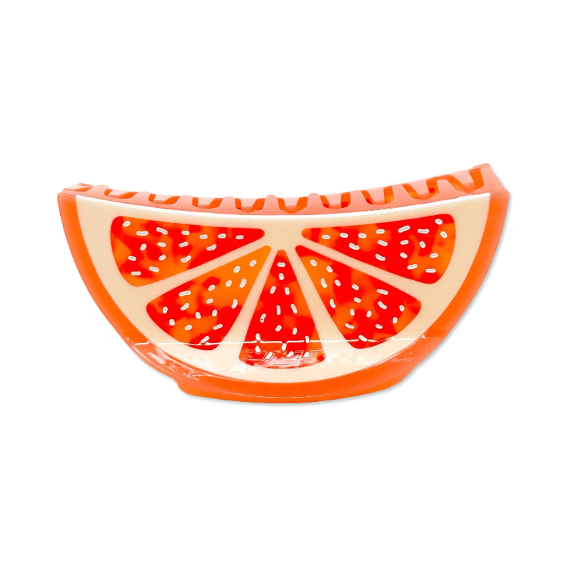 An orange slice-shaped product, likely a candle or decorative object, featuring a bright orange rind and red-orange interior segments with small white perforations, shown on a plain white background.