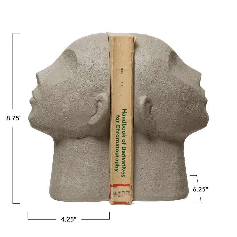 Stone head sculpture with a book for scale on a white background