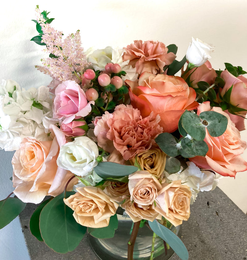 Bouquet of flowers with pink, orange, and white roses on a light background